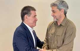 Cartes, con saco oscuro y camisa blanca, y Abdo Benítez, en camisa clara y jeans, se saludan sonriendo en un ambiente interior.