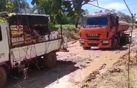 Un camioncito transportador de verduras ayuda a una cisterna del MOPC a salir del lugar donde quedó atrapado; es la zona donde están realizando los trabajos de remiendo.