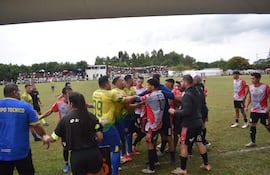 Jugadores de San José Mí y Atlético Corateí discuten acaloradamente en campo de fútbol, espectadores observando desde las gradas.
