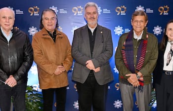 Cinco personas en trajes formales y un blazer posan en evento de la UIP. Fondo con insignia y mensaje de 90 años.
