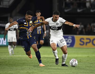 Walter González, futbolista de Olimpia, pelea el balón con César Benítez, jugador de Sportivo Trinidense, en un partido del torneo Clausura 2023 del fútbol paraguayo en el estadio Manuel Ferreira, en Asunción.