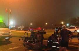 Vehículo de emergencia con luces verdes en una escena de neblina, mientras varias personas en uniforme asisten a un hombre herido.