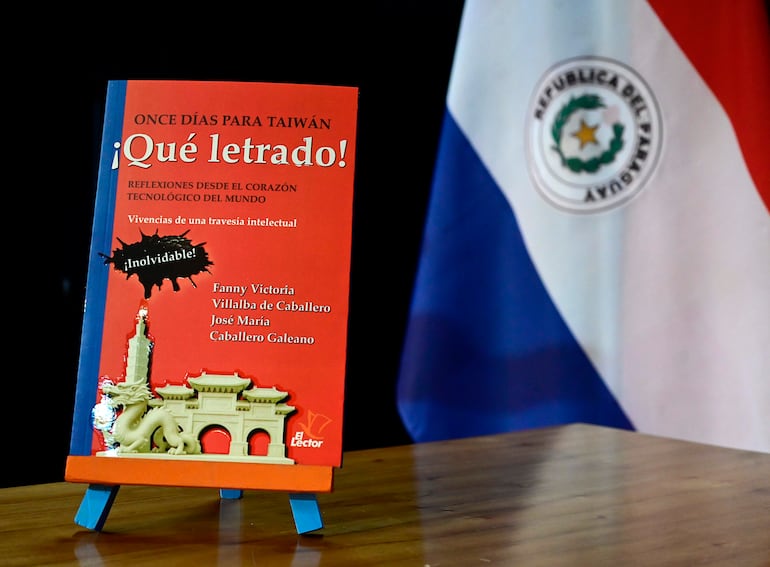 El libro '¡Qué letrado!' sobre una mesa con una bandera paraguaya de fondo, resaltando su diseño y color rojo.
