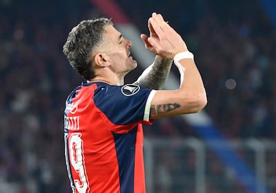 Jugador de Cerro Porteño, vistiendo camiseta roja y azul con el número 19, celebra con gesto de agradecimiento en estadio lleno de aficionados.