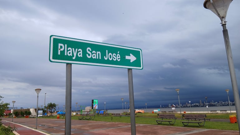 Letrero verde señaliza dirección a Playa San José, con cielos nublados y ambiente costero en Encarnación.