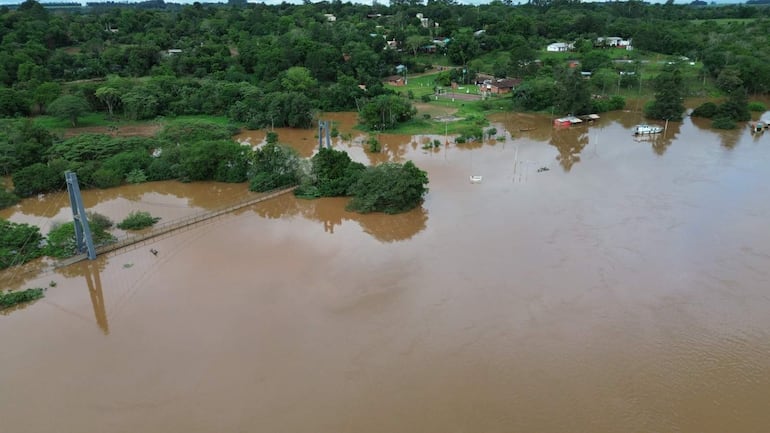 Vista aérea del puente colgante en medio de grandes extensiones de agua marrón, sin personas visibles en la escena.