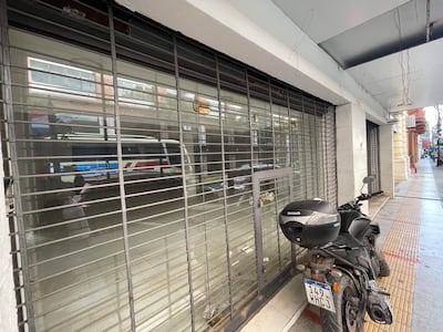 Calle desierta en Asunción con rejas metálicas de negocios cerrados y una motocicleta negra aparcada.