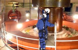 La foto permite comparar el tamaño del eje turbina-generador con el de los dos técnicos.