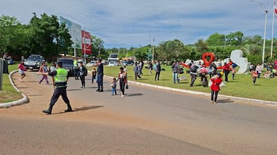 Grupo de indígenas en la rotonda de Coronel Oviedo, con presencia policial y familias caminando en un ambiente urbano.