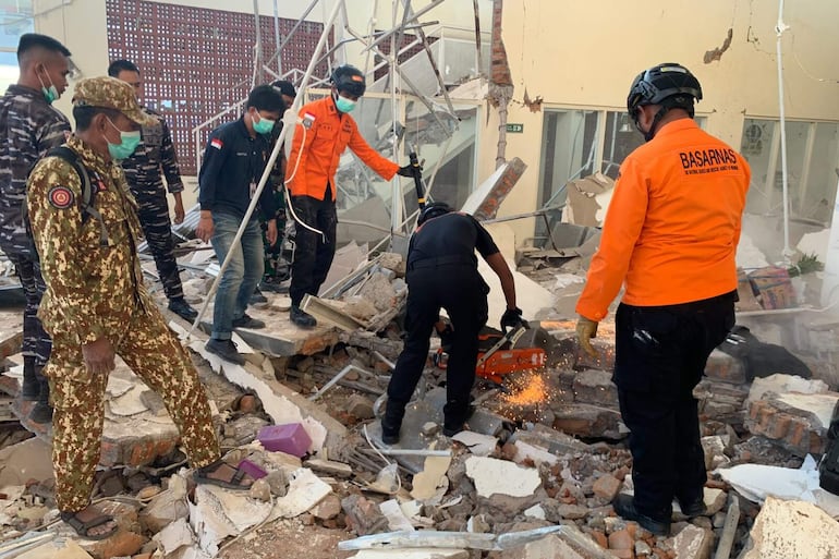 ISLA DE FLORES (INDONESIA) Fotografía cedida por la Agencia Nacional de Búsqueda y Rescate de Indonesia (Basarnas) de sus integrantes trabajando en un edificio derrumbado tras un terremoto de 7,7 registrado este sábado, en la isla de Flores (Indonesia). EFE