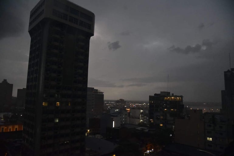 Cielo oscuro y nublado sobre edificios altos en Asunción, creando una atmósfera de tormenta. Sin personas en la imagen.