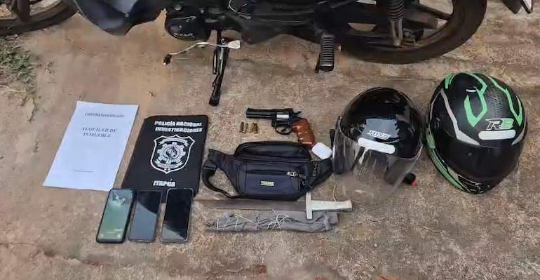 Escena de investigación policial con pistola, cascos y teléfonos en el suelo, documentos de la Policía Nacional presentes.