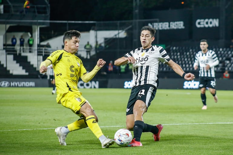 El zaguero de Recoleta FC intenta rechazar el esférico ante la marca del delantero de Libertad, Gustavo Aguilar.