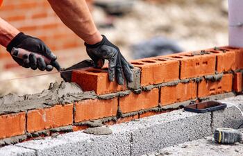 Un obrero trabaja en la construcción de un muro de ladrillos con cemento (foto de referencia).