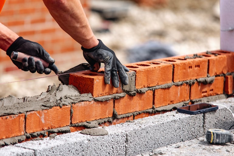 Un obrero trabaja en la construcción de un muro de ladrillos con cemento (foto de referencia).