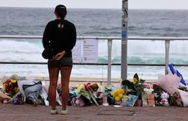 Una mujer se detiene ante ofrendas florales en Bondi Beach para rendir homenaje a las víctimas del tiroteo de Sídney, el 16 de diciembre de 2025.