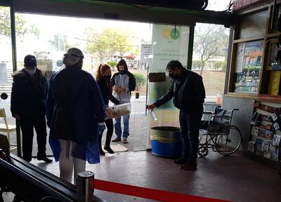 Un guardia de la Terminal de Ómnibus de Asunción desinfecta un contenedor de alimentos que ingresa una persona.