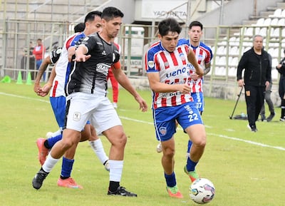 Blas Yamil Díaz, autor del gol de Tacuary, intenta frenar el avance de Jorge Pineda, ante la atenta mirada de Robert Pereira Molina, quien inició con empate su quinto ciclo como capitán del Buque barriojarense.