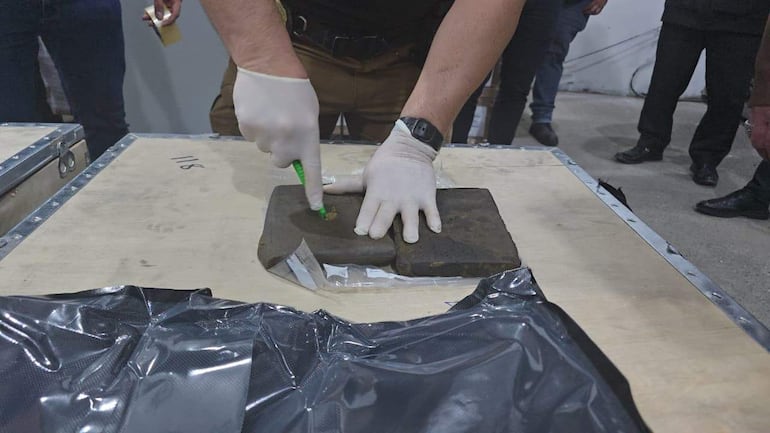 Un agente antidrogas manipula uno delos bloques de marihuana premium, que fueron incautados en el aeropuerto Silvio Pettirossi.
