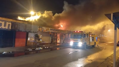 Escena de un incendio en la lomitería 'Despenza Deisy', con humo y llamas visibles. Vehículo de bomberos en la calle.