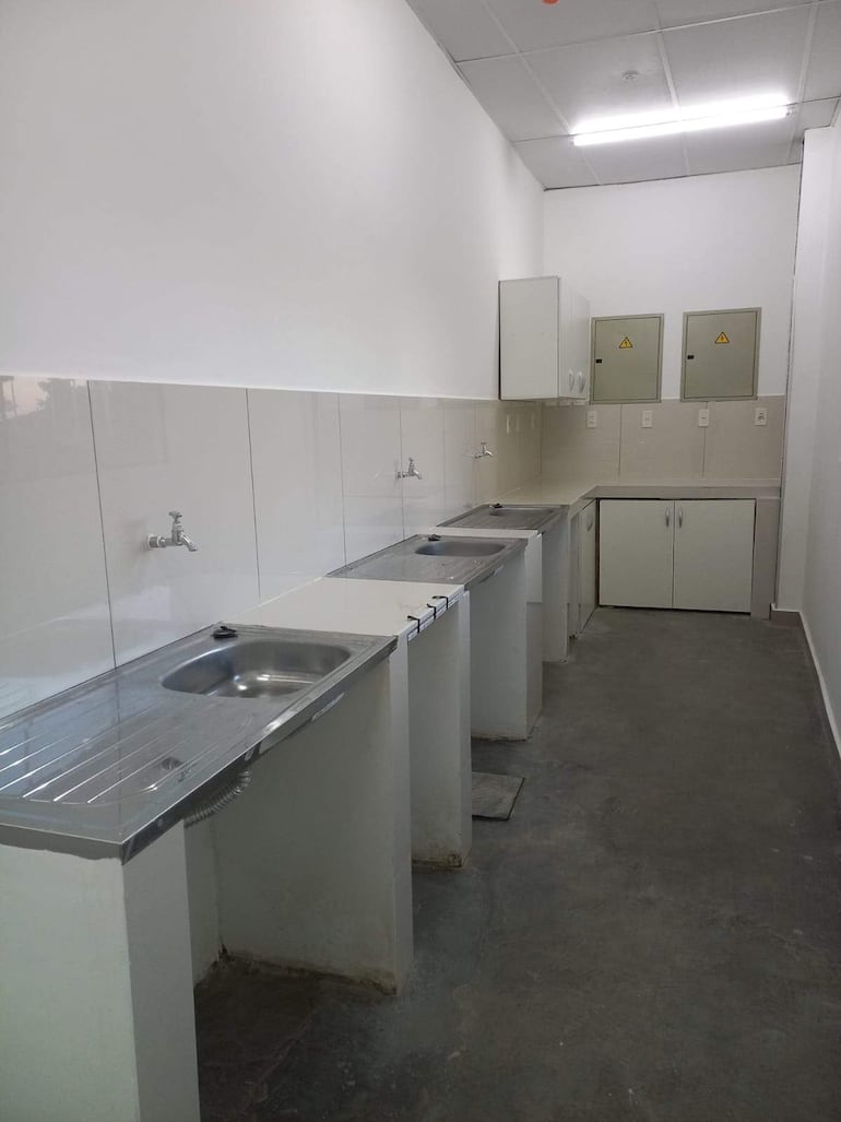 Espacio interior funcional con piletas de acero inoxidable y paredes blancas, sin personas presentes.