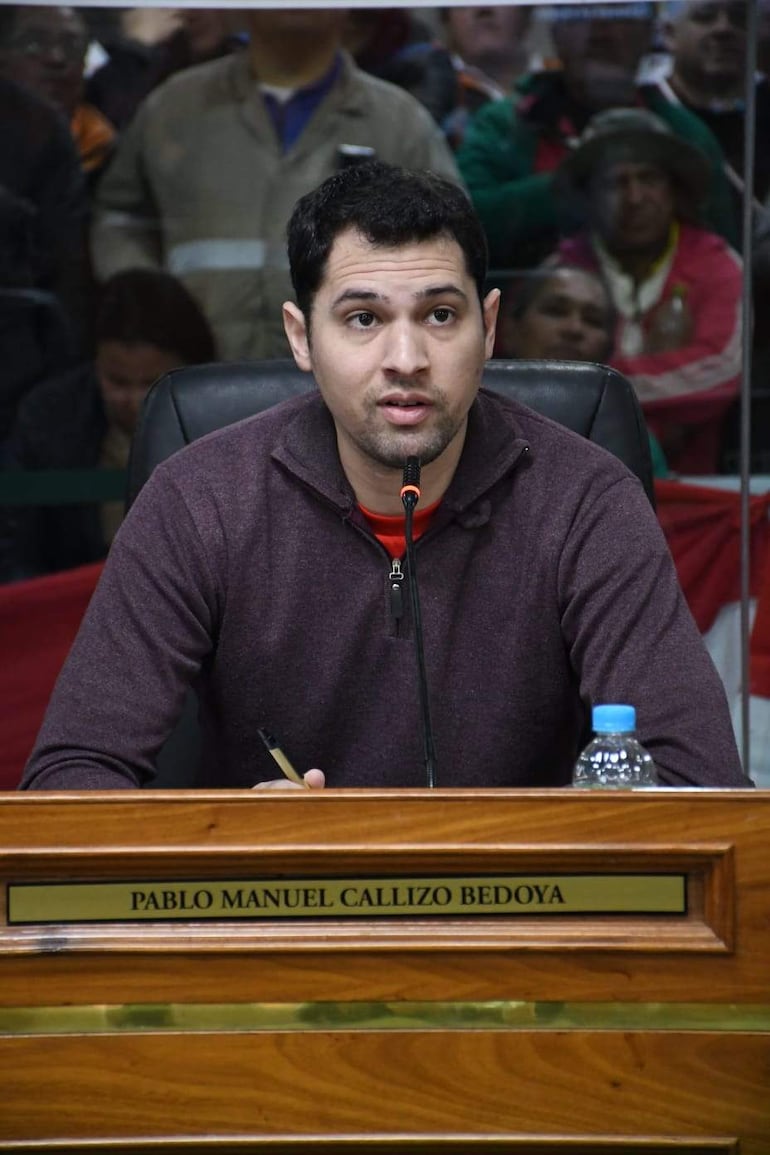 Pablo Callizo, con suéter morado y camiseta roja, habla frente a un micrófono ante un público atento.