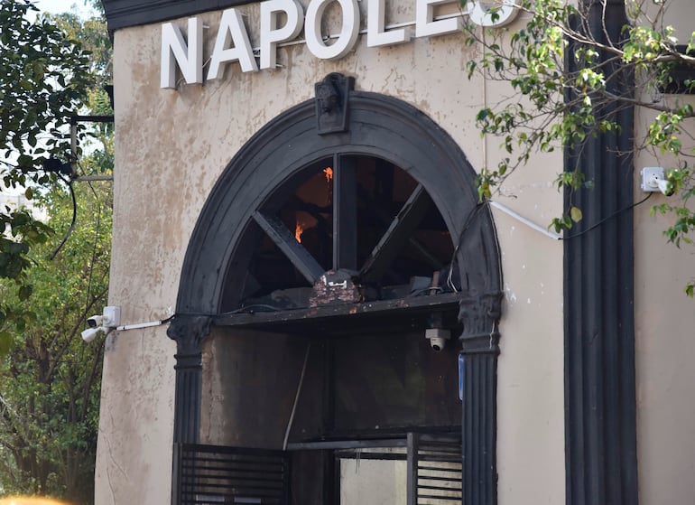 Edificio 'Napoles' dañado por incendio, con llamas visibles en la entrada y ventanas rotas.