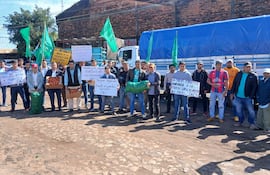 Grupo de campesinos con carteles y cajas de verduras, protestando en el cruce internacional, con banderas verdes de la FNC.