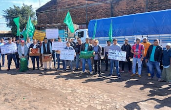 Grupo de campesinos con carteles y cajas de verduras, protestando en el cruce internacional, con banderas verdes de la FNC.