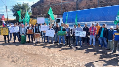 Grupo de campesinos con carteles y cajas de verduras, protestando en el cruce internacional, con banderas verdes de la FNC.