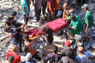 Rescatistas trasladan el cuerpo de una persona fallecida durante un bombardeo israelí a una escuela que albergaba a personas desplazadas en la Ciudad de Gaza, el domingo.
