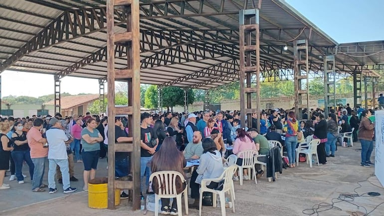 Gran cantidad de personas en el colegio Santa Librada, sentadas y de pie, en un ambiente de expectativa y diversidad.