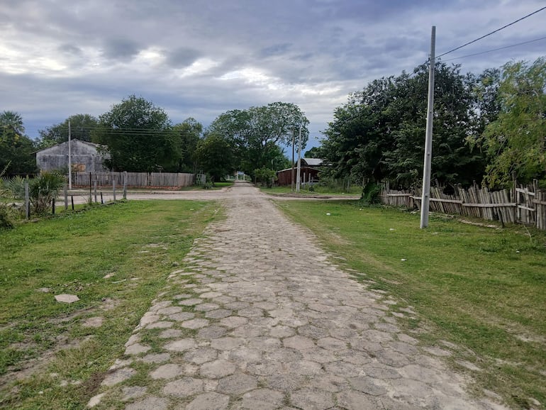 Calle empedrada rodeada de árboles y edificaciones deterioradas bajo un cielo nublado en Bahía Negra.