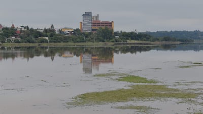 Entorno natural junto a un arroyo, reflejando edificaciones de colores variados en un ambiente tranquilo y deshabitado.