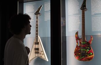 Un visitante observa una guitarra de Steve Vai, pintada con su propia sangre (derecha), en el nuevo museo que ha abierto este jueves en Barcelona, el 'Guitar Legends Hall', en el que se exhiben guitarras eléctricas tocadas por legendarios intérpretes, y que dispondrá de un área inmersiva e interactiva además de un pequeño escenario para actuaciones en directo.
