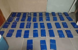 Espacio interior con suelo cubierto de bloques envueltos en plástico azul, indicando una incautación relacionada con contrabando.
