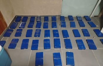 Espacio interior con suelo cubierto de bloques envueltos en plástico azul, indicando una incautación relacionada con contrabando.