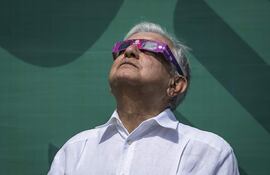 El presidente mexicano, Andrés Manuel López Obrador, usa gafas de sol especiales mientras observa un eclipse solar momentos antes de su totalidad, en Mazatlán, estado de Sinaloa, México,