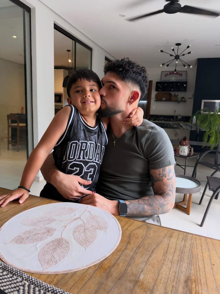Omar Alderete abraza a un niño sonriente con camiseta 'Jordan 23' en una mesa decorada con buen gusto.