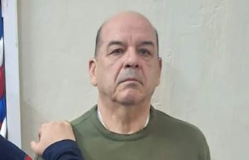 Miguel Ángel Robles de pie, con expresión seria y suéter verde oliva, mientras otro hombre lo toca levemente en el hombro.