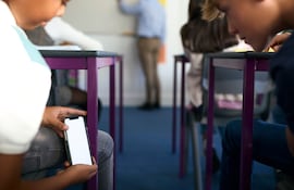 Dos niños revisan un teléfono celular en el aula.