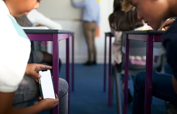 Dos niños revisan un teléfono celular en el aula.