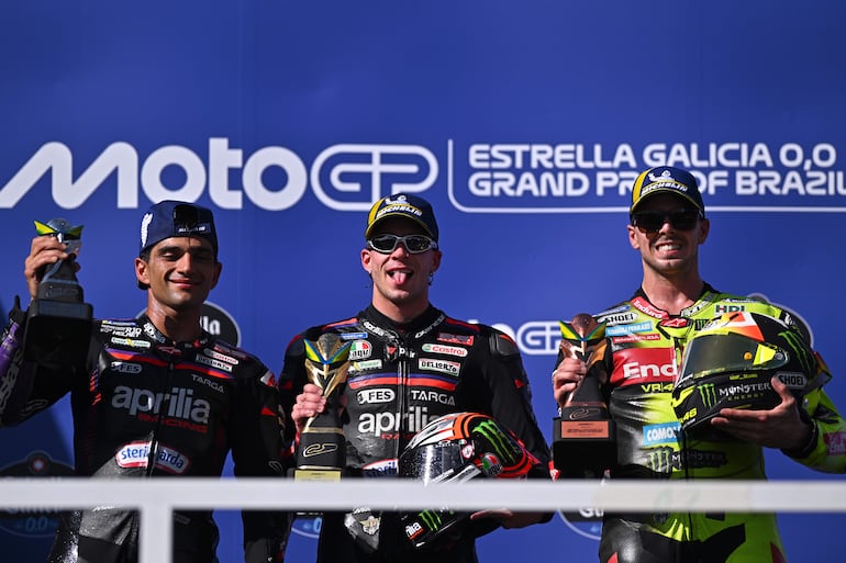 El italiano Marco Bezzecchi (centro), de Aprilia Racing, celebra en el podio al ganar el GP de Brasil de MotoGP junto al español Jorge Martin (izquierda), de Aprilia Racing, y al italiano Fabio Di Giannantonio, de Pertamina Enduro VR46 Racing Team.