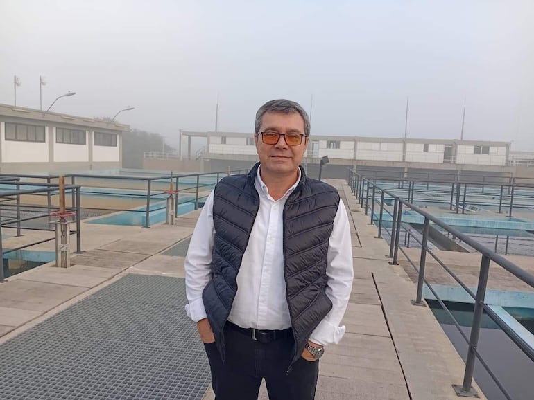 Richard Heurich, hombre de cabello canoso y chaleco negro, en planta de tratamiento con ambiente industrial y neblinoso.