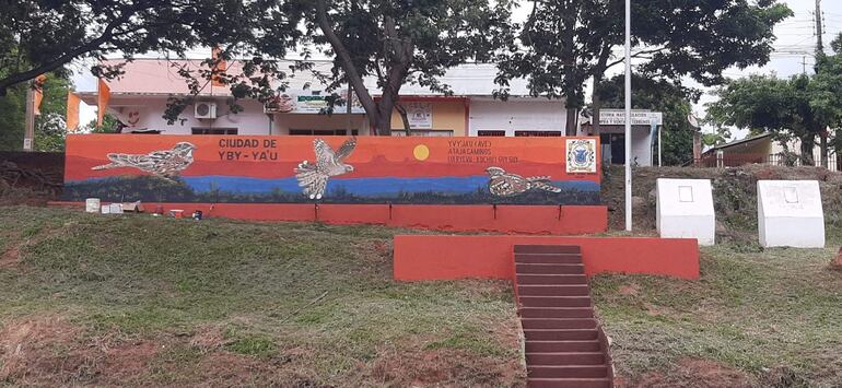 Mural colorido en Yby Yaú con el texto 'CIUDAD DE YBY-YA'U' y representaciones artísticas de aves.