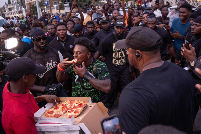El youtuber y streamer estadounidense Darren Jason Watkins Jr., más conocido como IShowSpeed (centro), come una porción de pizza durante un evento en el centro comercial Admiralty Mall, en Lagos, el 21 de enero de 2026.

