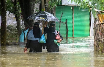 Dos personas cruzan a pie una zona inundada de la ciudad de Chattogram, Bangladés.