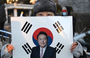 Un partidario del expresidente surcoreano destituido, Yoon Suk Yeol, sostiene una pancarta con su foto frente al Tribunal del Distrito Central de Seúl el 13 de enero de 2026, mientras se celebra el último juicio penal contra Yoon por cargos de insurrección.