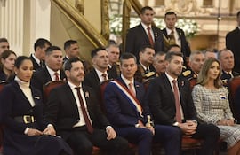 Raúl Latorre, vestido formalmente, sonríe junto a su esposa Jociani Repossi y Santiago Peña en un entorno ceremonial elegante.