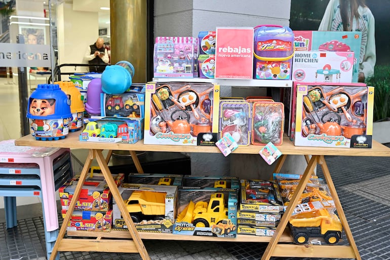 Exhibición de juguetes coloridos con letreros de rebajas frente a un local comercial moderno.